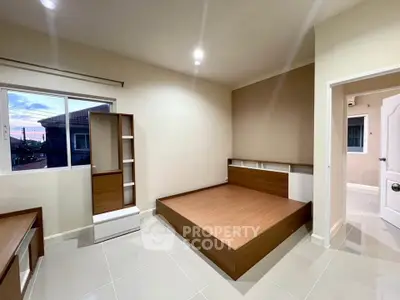 Spacious modern bedroom with sleek wooden furniture and large window offering natural light.