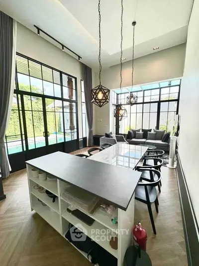 Modern open-layout living room with stylish furniture and large windows overlooking a pool.