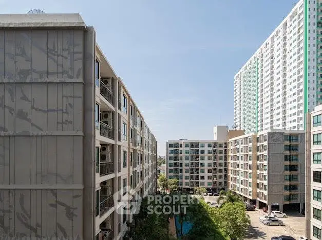 Modern apartment complex with multiple buildings and lush greenery under a clear blue sky.