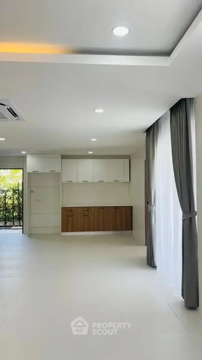 Spacious modern living room with large windows and elegant curtains, perfect for natural light and comfort.