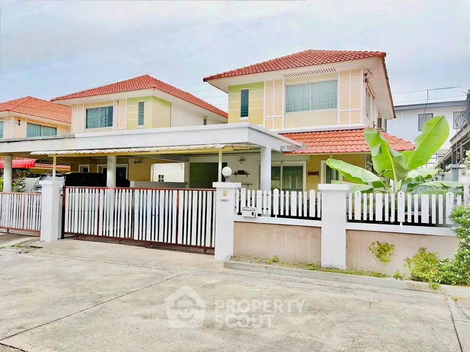Charming two-story house with red-tiled roof and white picket fence in a serene neighborhood.