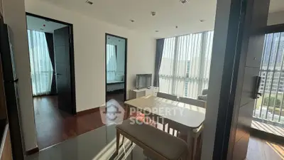 Modern apartment interior with open living and dining area, featuring large windows and natural light.