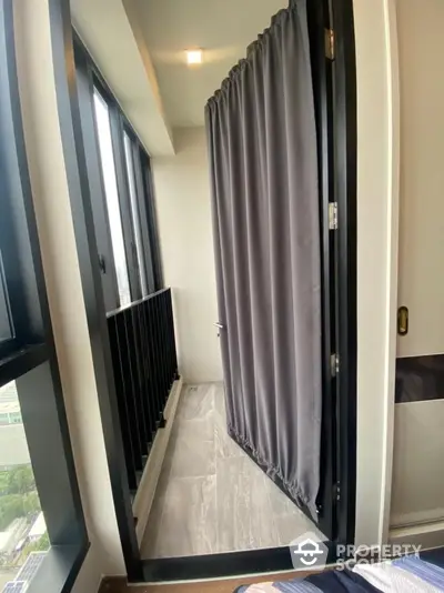 Modern apartment balcony with floor-to-ceiling windows and privacy curtains