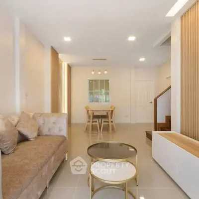 Modern living room with elegant furniture and open dining area, featuring stylish decor and ample natural light.