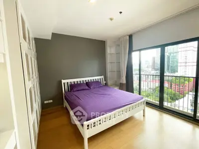 Spacious bedroom with city view and large windows in modern apartment.