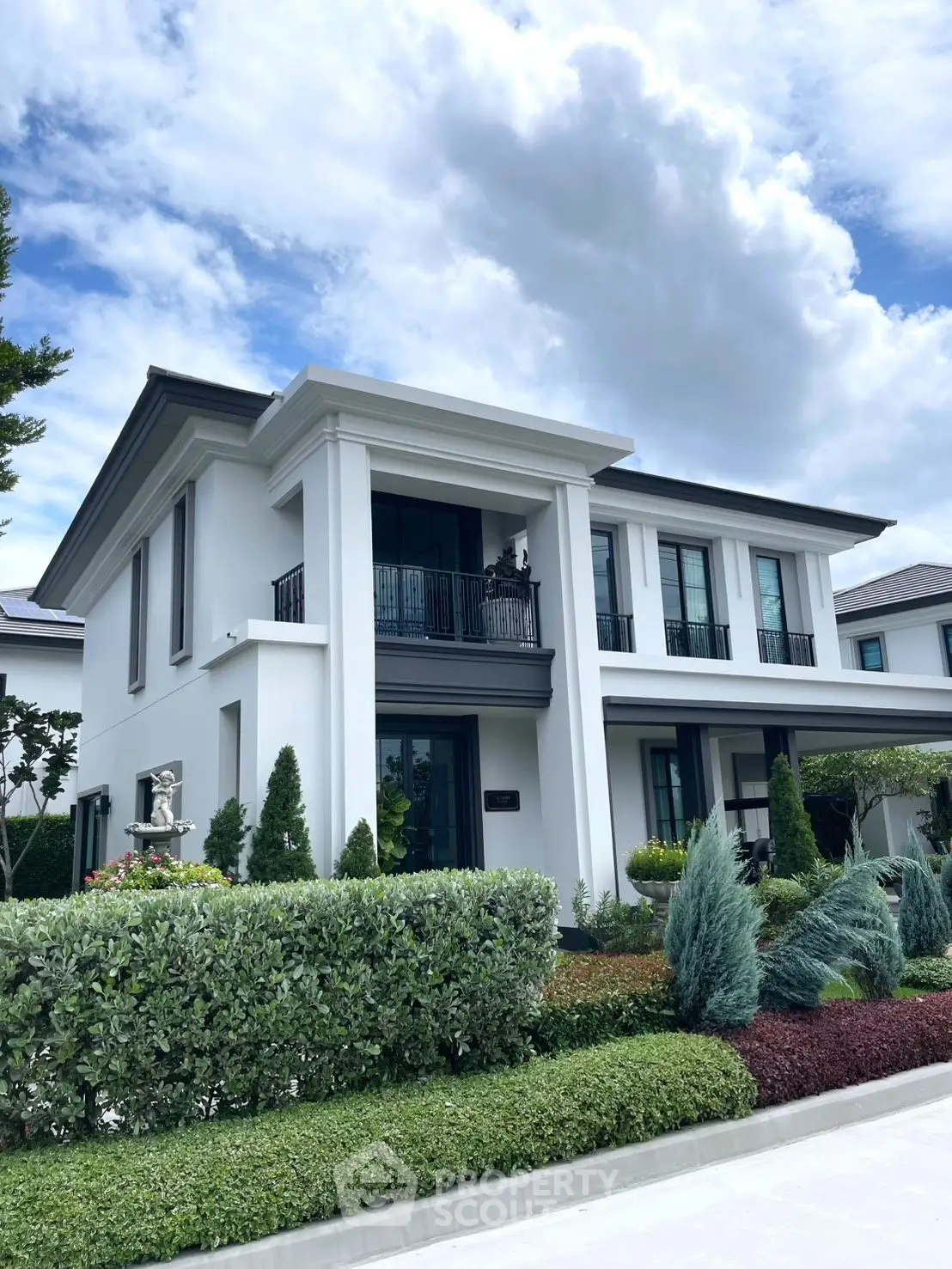 Stunning modern two-story house with lush garden and elegant facade under a vibrant sky.