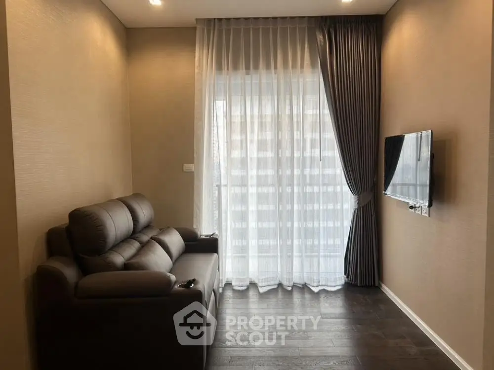 Cozy living room with plush sofa and modern TV setup, featuring elegant floor-to-ceiling curtains.