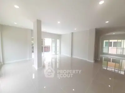 Spacious open-plan living area with glossy tiled floors and abundant natural light.
