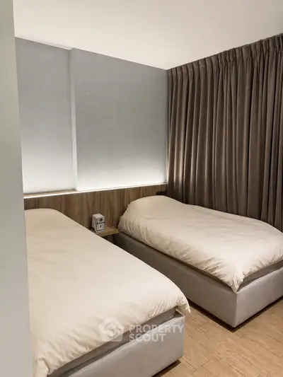 Modern twin bedroom with elegant lighting and floor-to-ceiling curtains