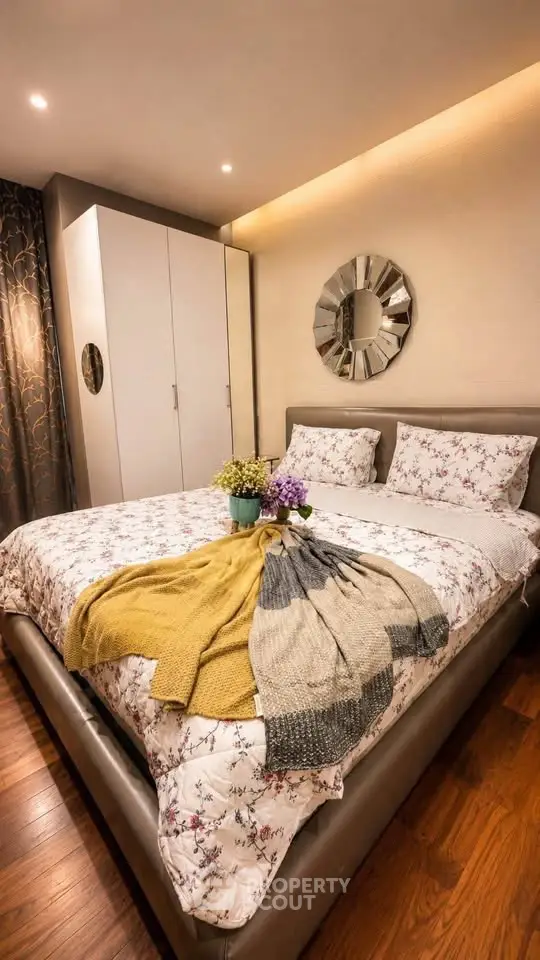Cozy bedroom with elegant decor and floral bedding, featuring a stylish wardrobe and decorative mirror.