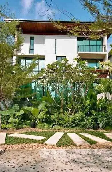 Modern building with lush garden and large glass windows, showcasing contemporary architecture.