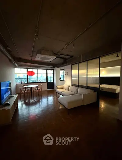 Modern industrial-style living room with large windows and cozy seating area.