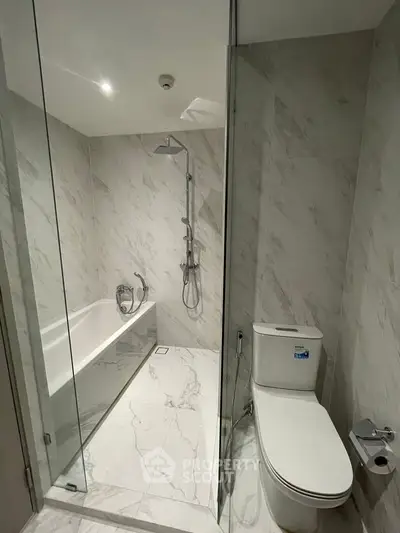 Luxurious marble bathroom with glass shower and modern fixtures in a high-end apartment.