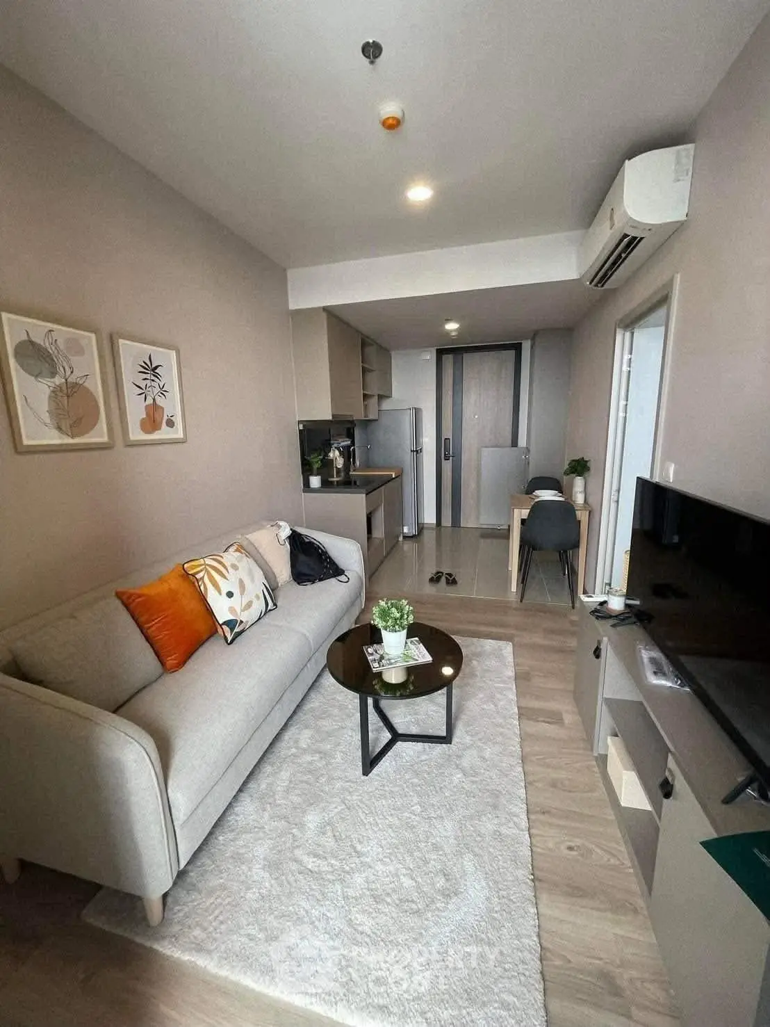 Modern living room with cozy sofa, stylish decor, and open kitchen layout in a chic apartment.