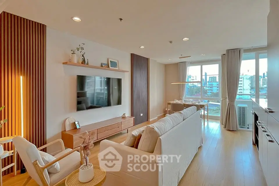 Spacious modern living room with large windows and stylish decor in urban apartment.