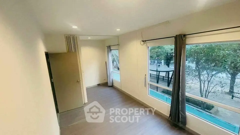 Spacious room with large windows offering serene garden views, perfect for a tranquil living experience.