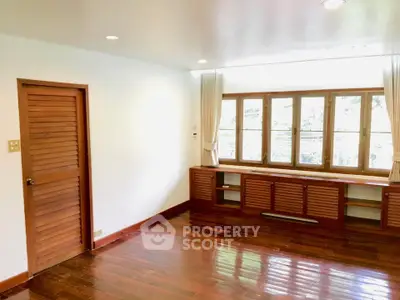 Spacious living room with wooden floors and large windows for natural light.