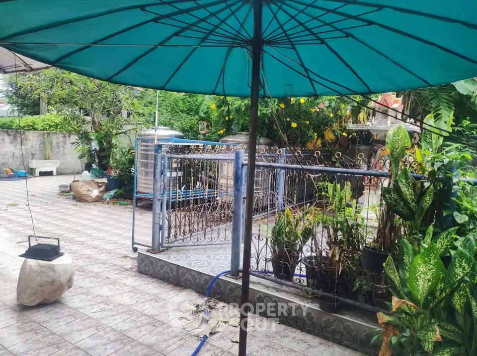 Spacious outdoor patio with lush greenery and decorative railing, perfect for relaxation and entertainment.