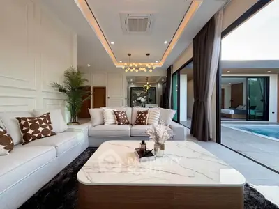 Luxurious living room with modern decor and pool view, featuring elegant lighting and spacious seating.