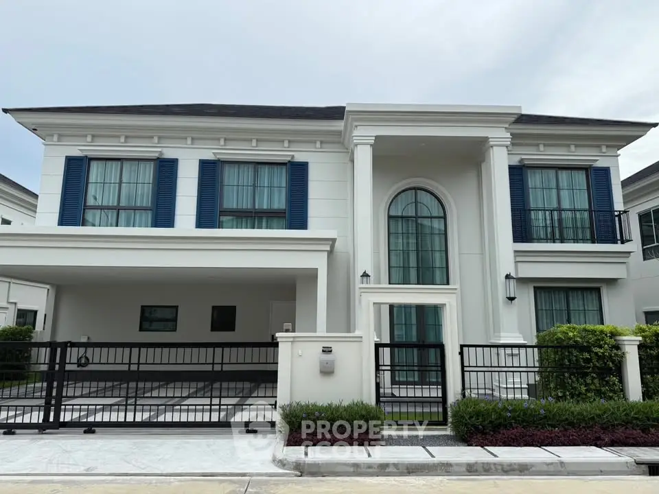 Elegant two-story house with classic columns and blue shutters in a serene neighborhood.