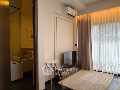 Modern living room with TV, air conditioning, and natural light from large window.