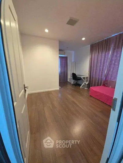 Spacious bedroom with wooden flooring and modern furnishings in a stylish apartment.