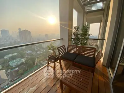 Stunning high-rise balcony with panoramic city view and cozy seating area at sunset.