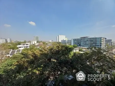 Stunning cityscape view with modern buildings and lush greenery under a clear blue sky.