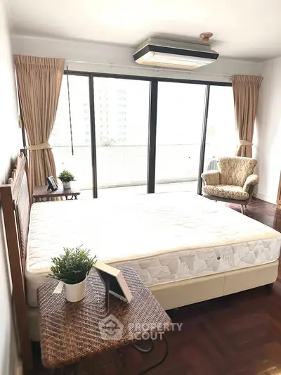 Spacious bedroom with large windows and balcony access in modern apartment.