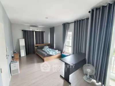 Spacious bedroom with modern decor and large windows for natural light.