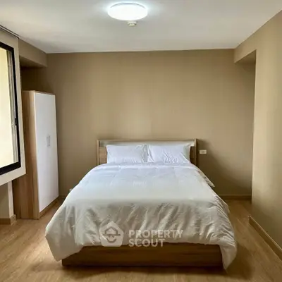 Cozy bedroom with minimalist design and natural light, featuring a comfortable bed and wooden flooring.
