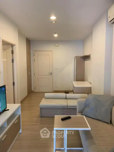 Modern living room with minimalist decor and neutral tones, featuring a cozy sofa and sleek TV stand.