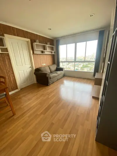 Spacious living room with large windows offering stunning city views, wooden flooring, and modern shelving.