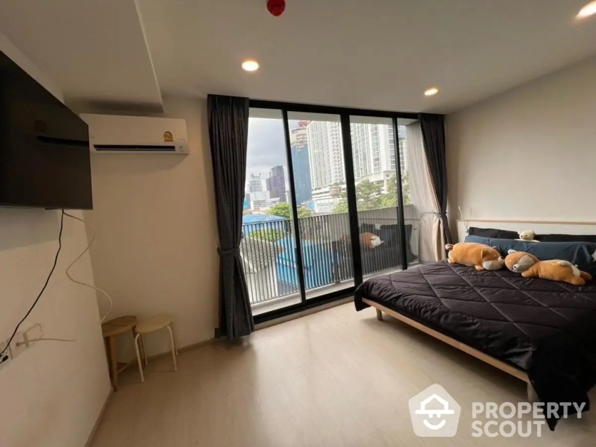 Modern bedroom with city view and large windows in high-rise apartment.