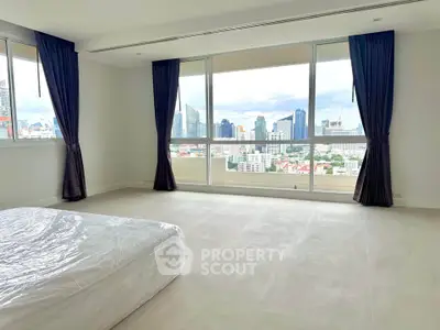 Spacious bedroom with stunning city view and large windows in modern apartment.