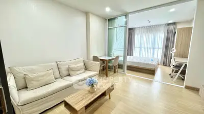 Modern living room with cozy sofa and view into bright bedroom