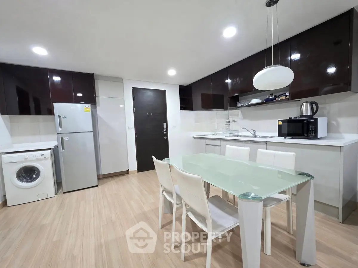 Modern kitchen with sleek appliances and dining area in contemporary apartment.