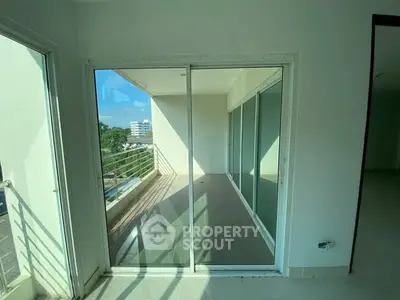 Spacious balcony with sliding glass doors and city view, perfect for relaxation.