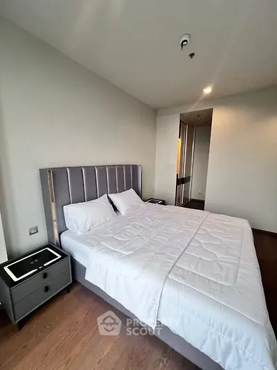 Modern bedroom with stylish bed and wooden flooring in a contemporary apartment.