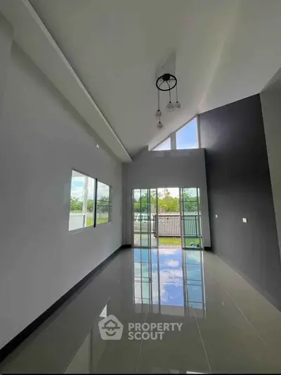 Spacious modern living room with high ceiling and large windows offering natural light and garden view.