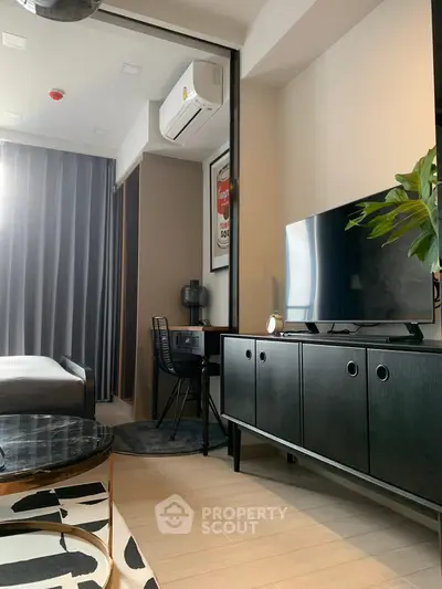 Modern living room with sleek furniture and stylish decor, featuring a TV and air conditioning unit.