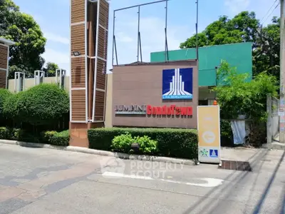 Modern condominium entrance with lush greenery and clear signage