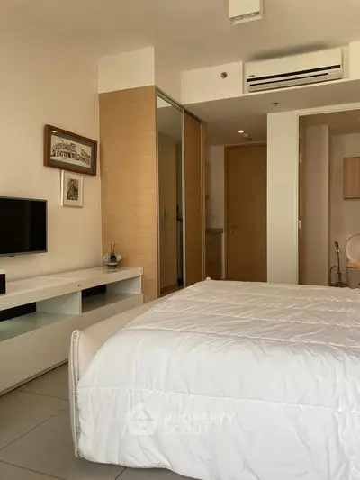 Modern bedroom with sleek design, featuring a cozy bed, built-in wardrobe, and air conditioning unit.