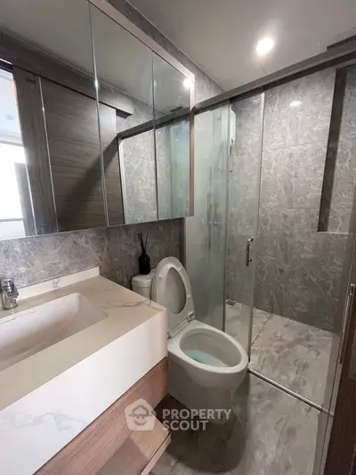Modern bathroom with glass shower and marble tiles in luxury apartment.
