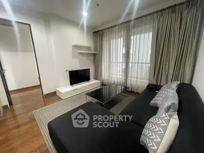 Modern living room with sleek black sofa, stylish decor, and large window for natural light.