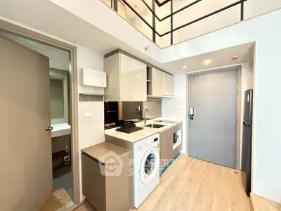 Modern loft-style apartment with sleek kitchen and washing machine, ideal for urban living.