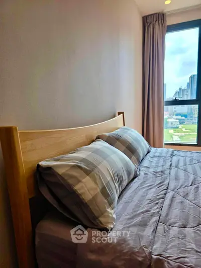 Cozy bedroom with city view, featuring a comfortable bed and large window for natural light.