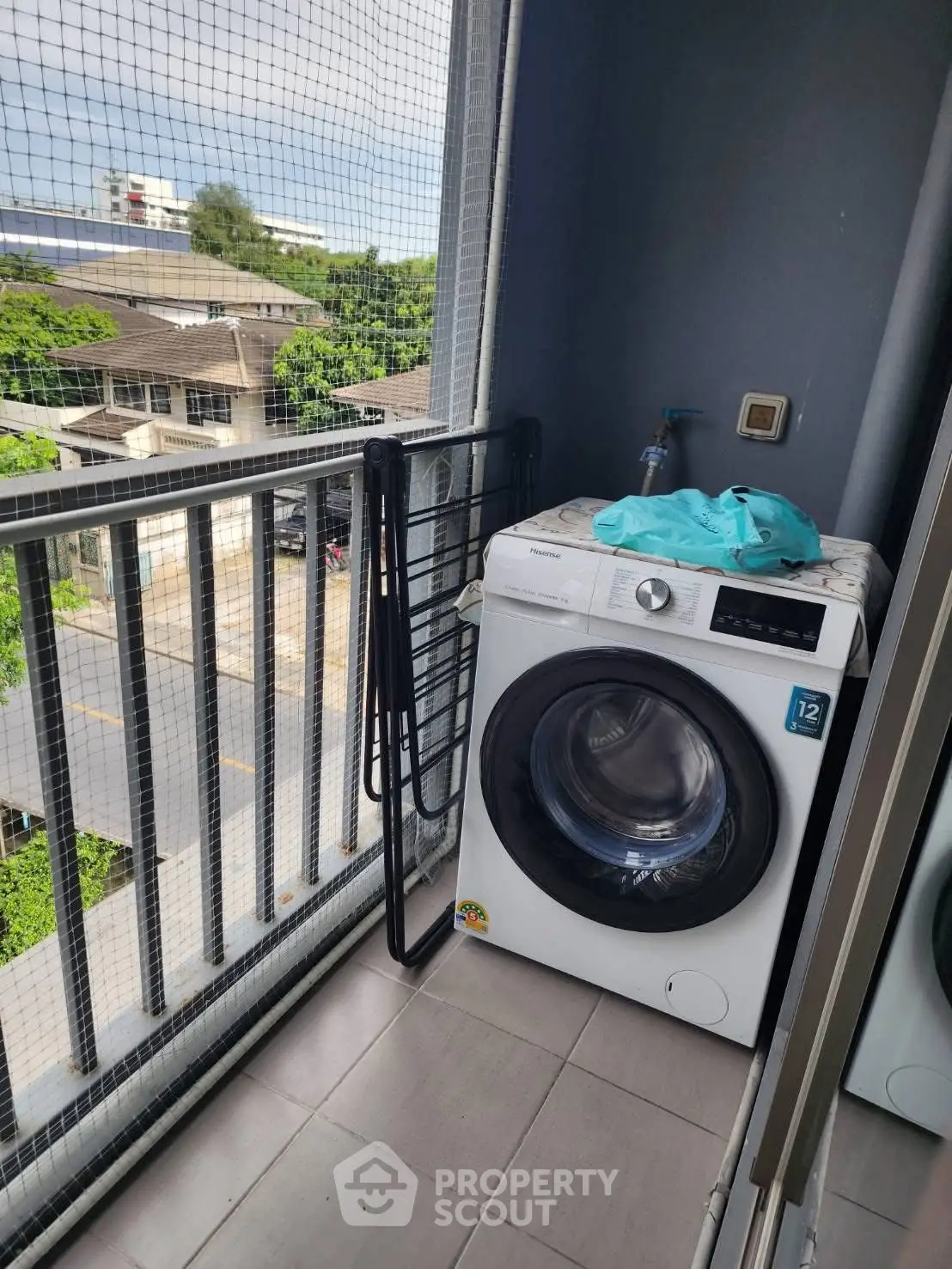 Compact balcony with washing machine and city view, ideal for urban living.