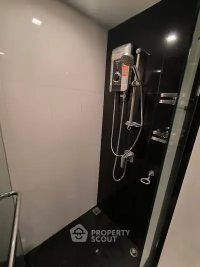 Modern bathroom with sleek black and white tiles and a high-end shower system.