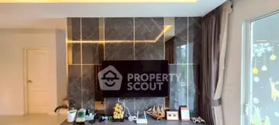Modern living room with sleek marble accent wall and large TV, perfect for entertainment.